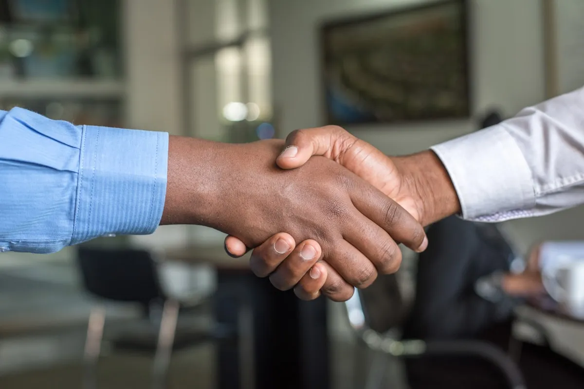 Two people shaking hands in a meeting room