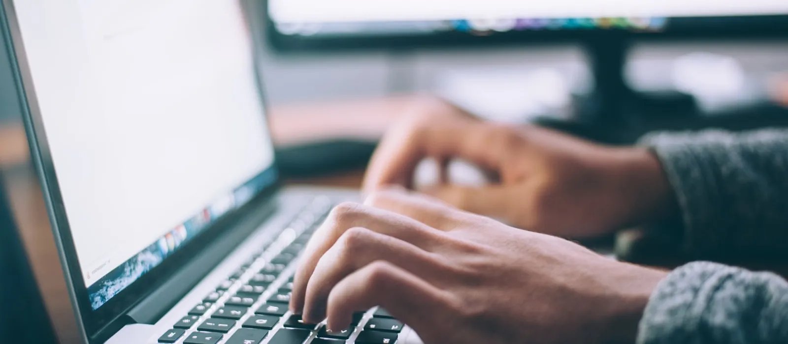 Person working at a desktop workstation with two screens